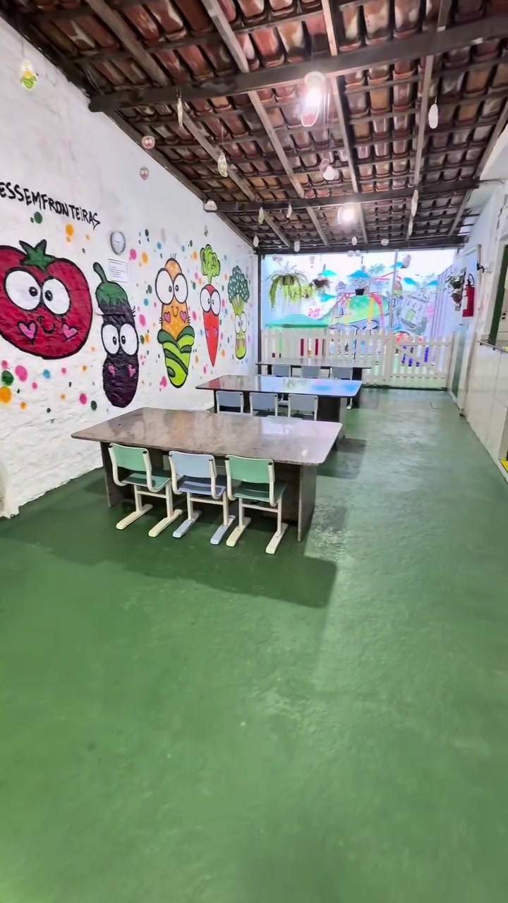 Refeitório com mesas infantis e mural de frutas